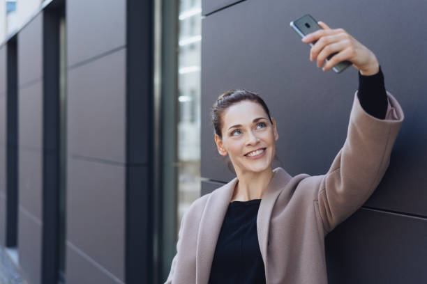 lächelnde junge frau unter ihrem selfie - netting women brown hair outdoors stock-fotos und bilder