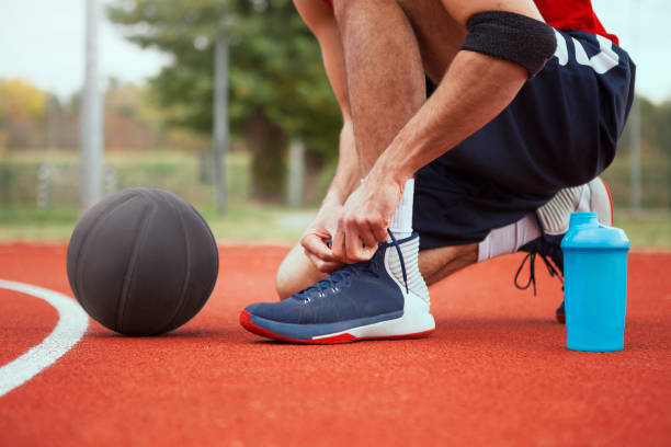 jugador de baloncesto atar cordones de los zapatos en cancha de baloncesto - basketball basketball player shoe sports clothing fotografías e imágenes de stock