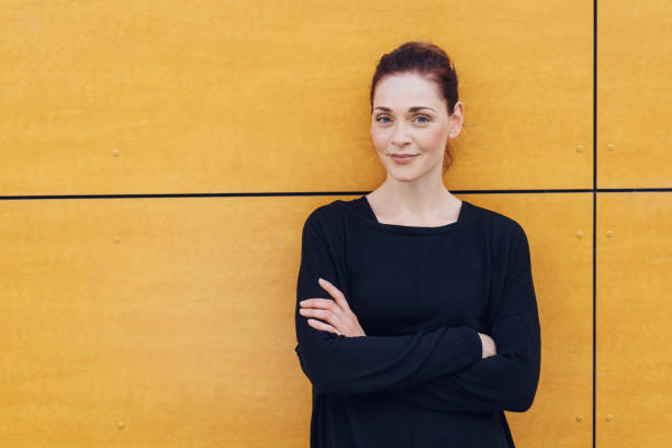 istock Smiling woman with folded arms against urban wall 1071399420