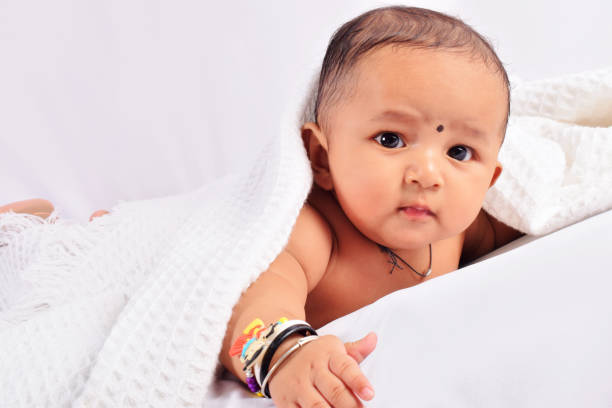 istock Cute baby sleeping on bed on stomach looking at camera, Pune, Maharashtra. 1071399656