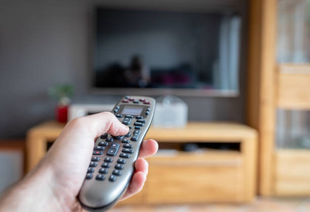istock A male hand holds a modern remote control and points to the TV 1071400680