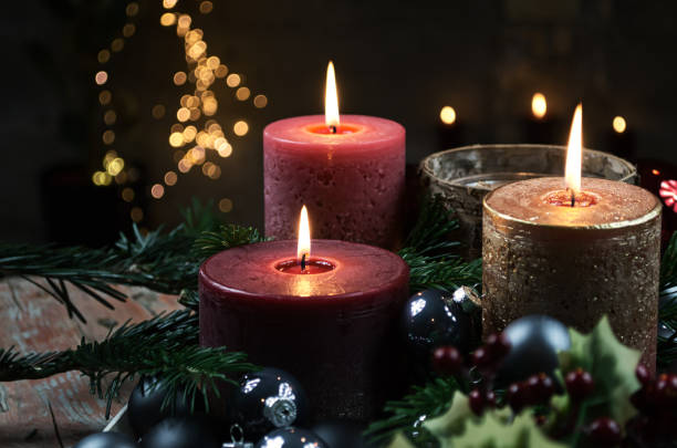 istock Three lighted candles amidst Christmas decorations on dark background 1071407210