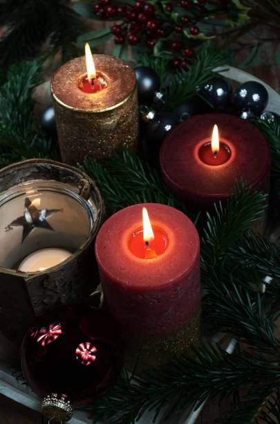 istock Three lighted candles amidst Christmas decorations on dark background 1071407214