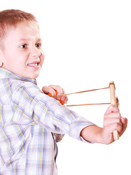 istock Young boy use sling shot shoot mandarine. 1071409576