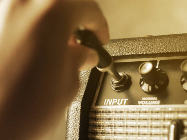 istock guitar amplifier with hand on cable audio jack, warm tone 1071411270