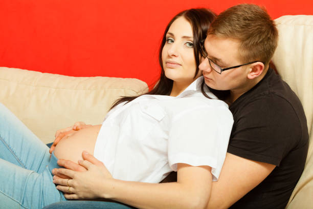 istock Pregnant woman and man relaxing on sofa 1071411552