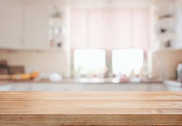 Empty wooden tabletop over defocused kitchen background with copy space