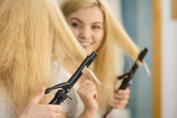 istock Woman using hair curler 1071416212