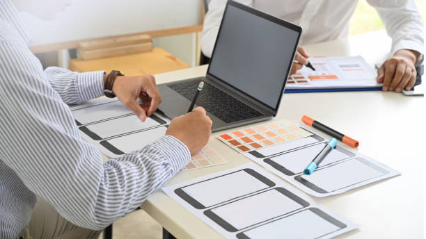 istock UI UX designer sketching layout design  application on mockup mobile phone in studio. 1071418742