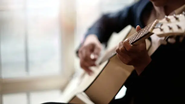 Photo of Cropped shot of man practicing in playing acoustic guitar