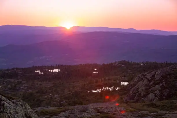 Sunset above mountain. Beautiful view of pink sky and golden sun, Central Norway, Kongsberg. Trees and lakes