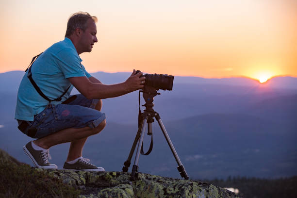 człowiek z kamerą i statywem filmowanie zachód słońca nad górą. - high peaks audio zdjęcia i obrazy z banku zdjęć