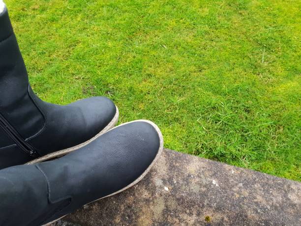 istock Black leather boots against background of grass with copy space 1071429614
