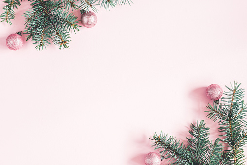 Christmas composition. Frame made of fir tree branches, pink balls on pastel pink background. Christmas, winter, new year concept. Flat lay, top view, copy space