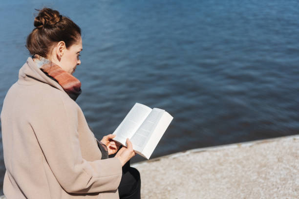 istock Woman sitting at the seaside reading a book 1071444288