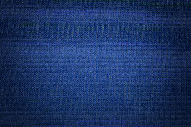 Navy blue background from a textile material with wicker pattern, closeup. Dark azure background from a textile material with wicker pattern, closeup. Structure of the navy blue fabric with texture. Cloth denim backdrop with vignette. flax weaving stock pictures, royalty-free photos & images