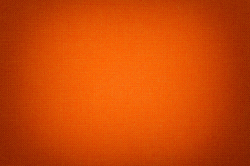 Dark orange background from a textile material with wicker pattern, closeup. Structure of the bright red fabric with texture. Cloth backdrop with vignette.
