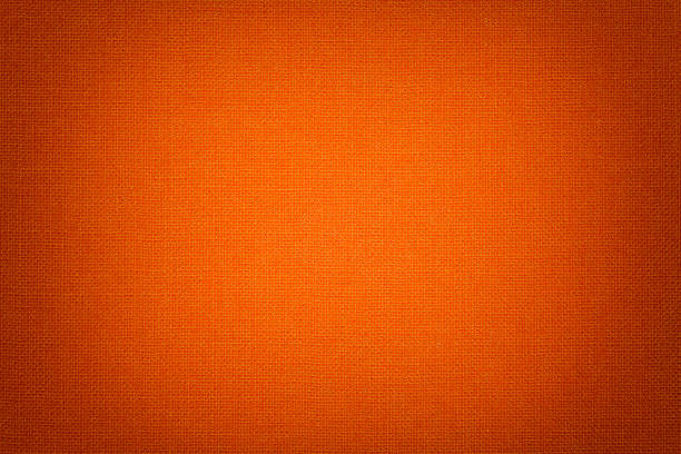 Bright orange background from a textile material with wicker pattern, closeup. Dark orange background from a textile material with wicker pattern, closeup. Structure of the bright red fabric with texture. Cloth backdrop with vignette. flax weaving stock pictures, royalty-free photos & images
