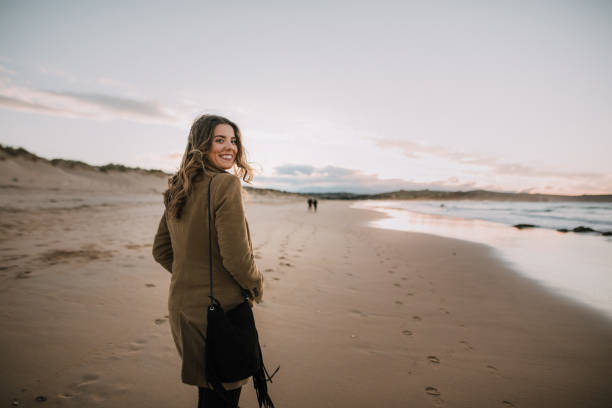 istock Young woman walking over a beach in winter at sunset 1071449012