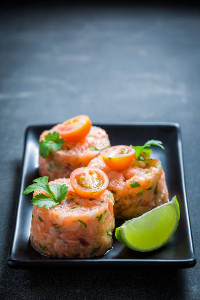 istock Salmon tartare with lime and cherry tomatoes on concrete table 1071451384