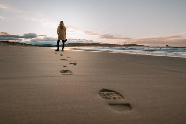 junge frau zu fuß über den strand und hinterlassen ihre spuren im sand - footprint sand sea beach stock-fotos und bilder