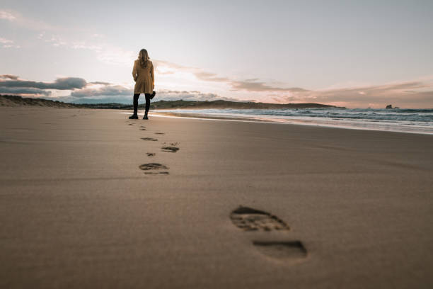 joven mujer caminando sobre una playa y dejando sus huellas en la arena - footprint sand sea beach fotografías e imágenes de stock