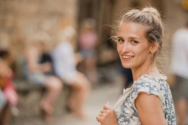Portrait of a young female adult turning as she walks down a street in the old town, Volterra.