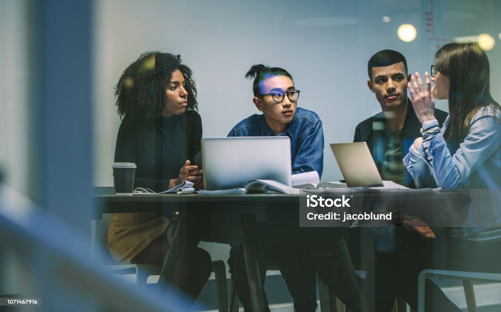 Grupo de jóvenes estudiantes trabajando en una asignación - Foto de stock de Tecnología libre de derechos