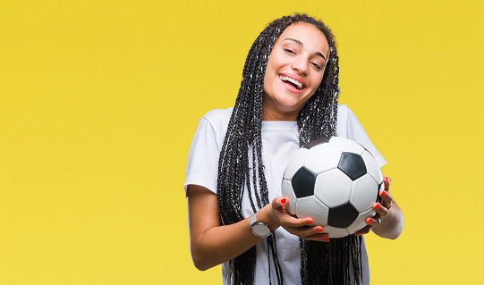 Young braided hair african american girl holding soccer ball over isolated background with a happy face standing and smiling with a confident smile showing teeth
