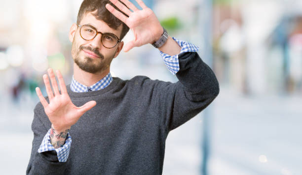 istock Young handsome smart man wearing glasses over isolated background Smiling doing frame using hands palms and fingers, camera perspective 1071468476