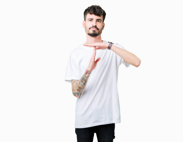 istock Young handsome man wearing white t-shirt over isolated background Doing time out gesture with hands, frustrated and serious face 1071468648