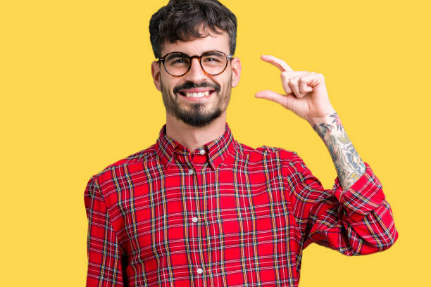 istock Young handsome man wearing glasses over isolated background smiling and confident gesturing with hand doing size sign with fingers while looking and the camera. Measure concept. 1071469074