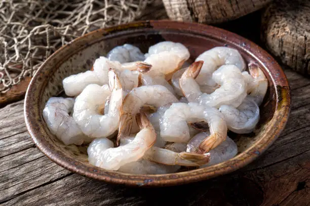 A bowl of fresh raw pacific white shrimp peeled with tail on.