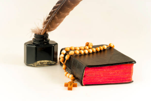 istock Book with a rosary, and an inkwell with a bird feather on a white background 1071484864