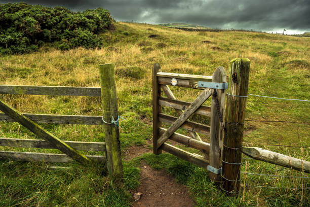 Open Wooden Gate In Fence With Rocky Trail To Grassy Pasture stock photo