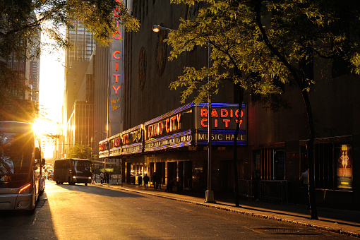New York, USA - June 22, 2016. Radio City Music Hall on 6th Avenue at sunset with people walking on sidewalk, New York City, USA