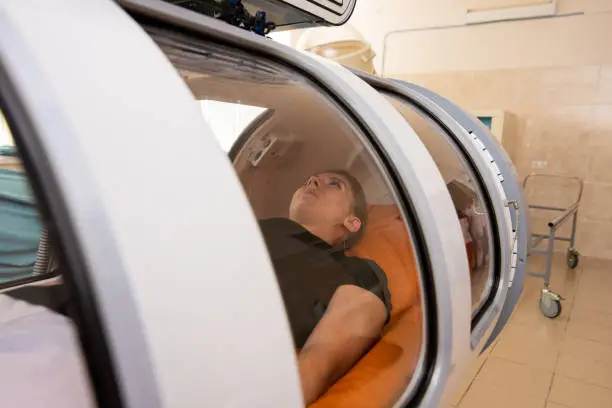 Photo of beautiful girl in a black T-shirt lies in a hyperbaric chamber