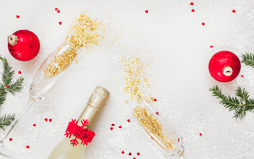 Christmas celebration. Champagne bottle and glasses with gold confetti lying on festive table. Top view, blank space