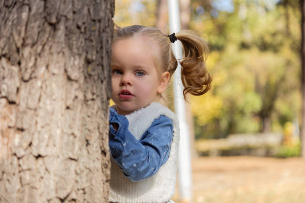 istock Beautiful Baby Girl Hiding Behind A Tree 1071555306
