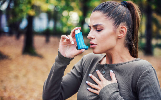 giovane donna che cura l'asma con inalatore - asthmatic foto e immagini stock