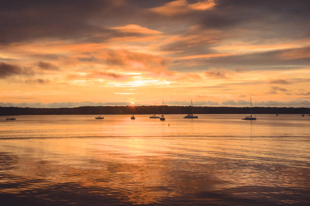 Harbor Sunset Sailboats anchored off the shore of Three Mile Harbor, East Hampton, during a surreal summer sunset. the hamptons stock pictures, royalty-free photos & images