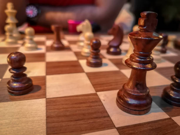 istock Men playing chess - King and chess pieces on a wooden board 1071570958