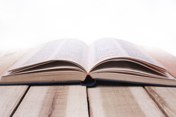 istock Opened Book on Wooden Table Against White Background 1071571344