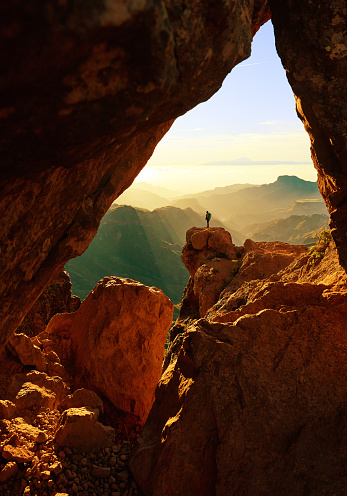 amazing shot of hiker on top of mountains admiring view over Grand Canary mountains.