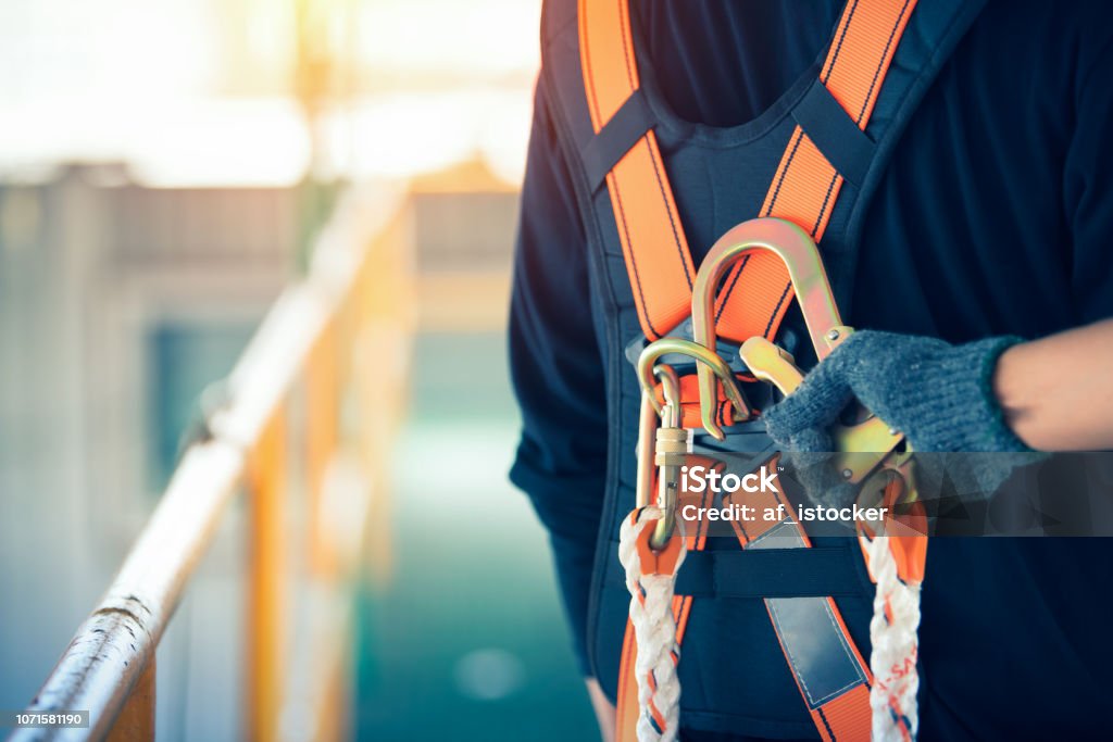 Trabajador de construcción usando cinturones de seguridad y línea de seguridad en lugar alto - Foto de stock de Seguridad libre de derechos