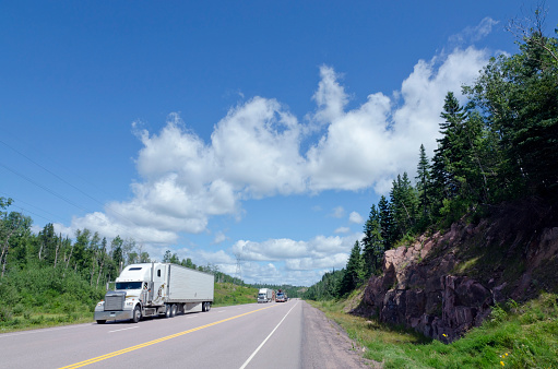 Cargo truck on Trans Canada Highway under cloud blue sky