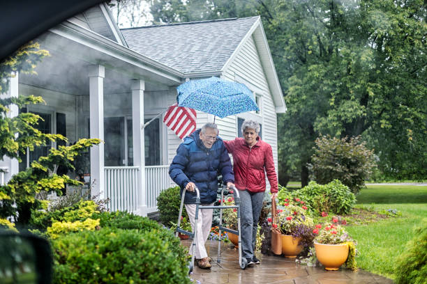 home caregiver daughter holding umbrella helping elderly father - rain drenched men wet imagens e fotografias de stock