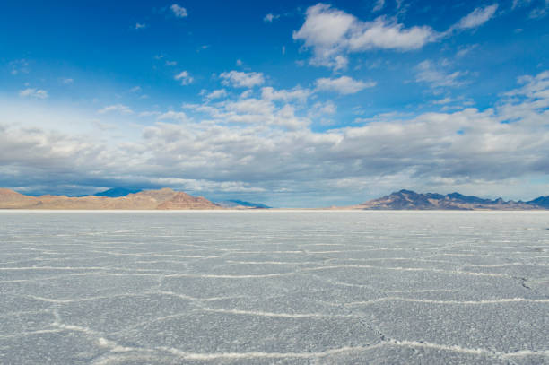 Stunning, Wide Open Vistas of the Bonneville Salt Flats in Utah This is a view of the Bonneville Salt Flats area, right at the edge of the Utah and Nevada border.  This is the site of many world land speed records because the flat, salt covered ground makes an excellent long-distance race trace.  The ground looks a little like it is covered in snow, but the white ground is salt.  There was some moisture on the ground from a recent rain. bonneville salt flats stock pictures, royalty-free photos & images