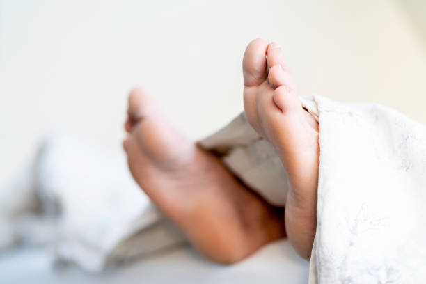 Feet of senior man poking out from duvet Feet of senior man poking out from duvet on bed in morning light protruding stock pictures, royalty-free photos & images