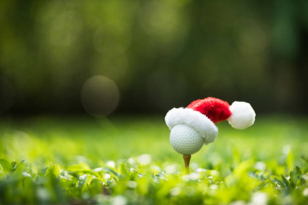 festive-looking golf ball on tee with santa claus' hat on top - tee golf golf ball ball imagens e fotografias de stock